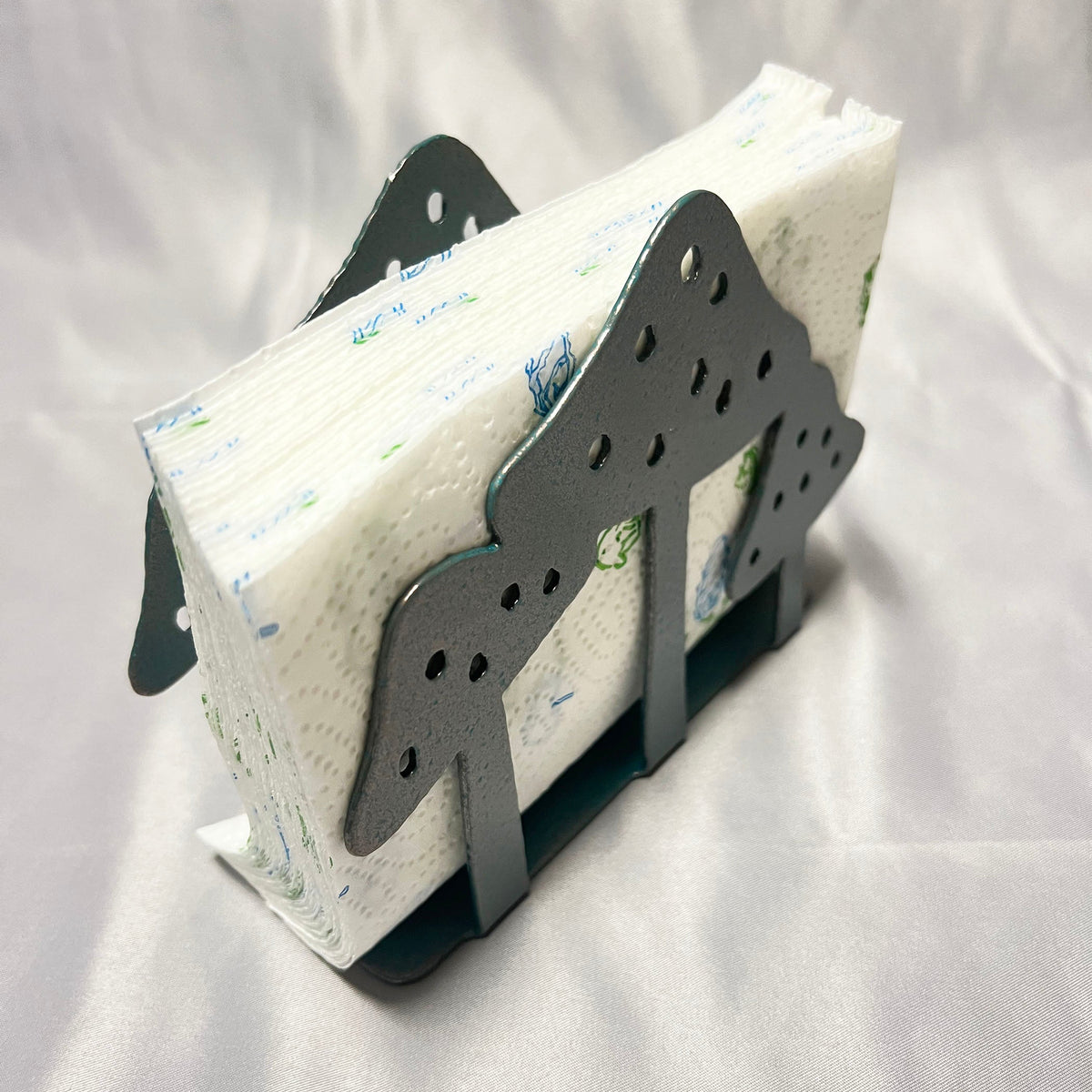 Angled view of metal mushroom napkin holder filled with white paper napkins