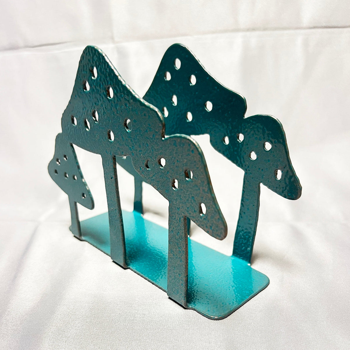Angled view of handmade steel mushroom napkin holder with turquoise base