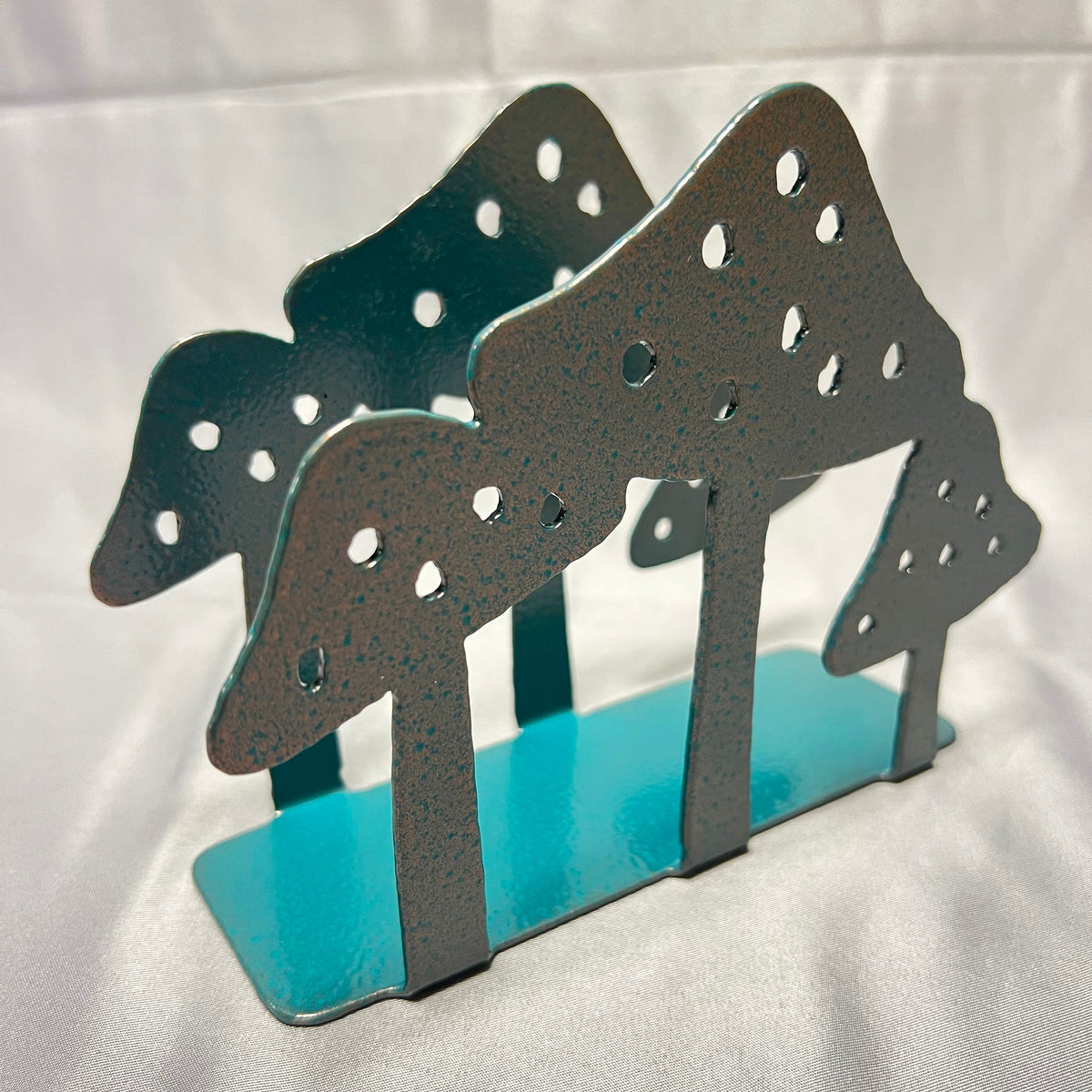 Three-quarter view of metal mushroom napkin holder showing decorative panels on both sides