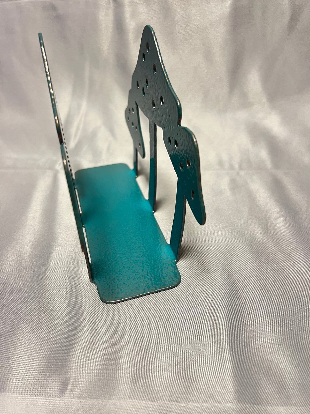 Side view of empty metal mushroom napkin holder showing spacing between panels