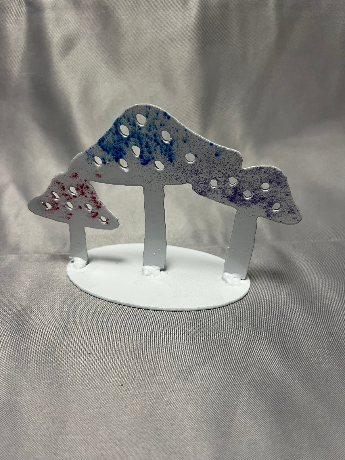 Front view of handmade colorful metal mushroom stand with white base