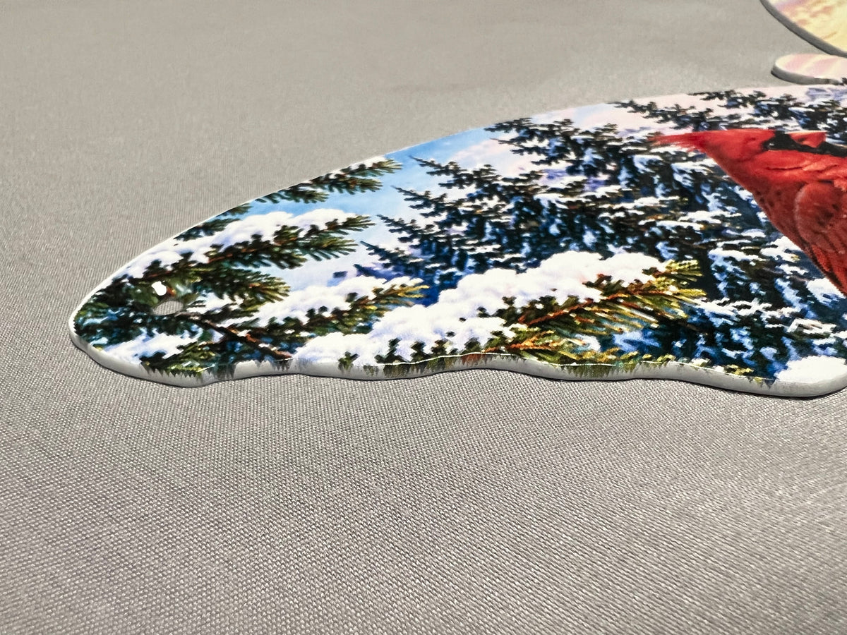 Close-up of snowy evergreen forest and reflective mountain lake artwork on the butterfly metal wall hanging.