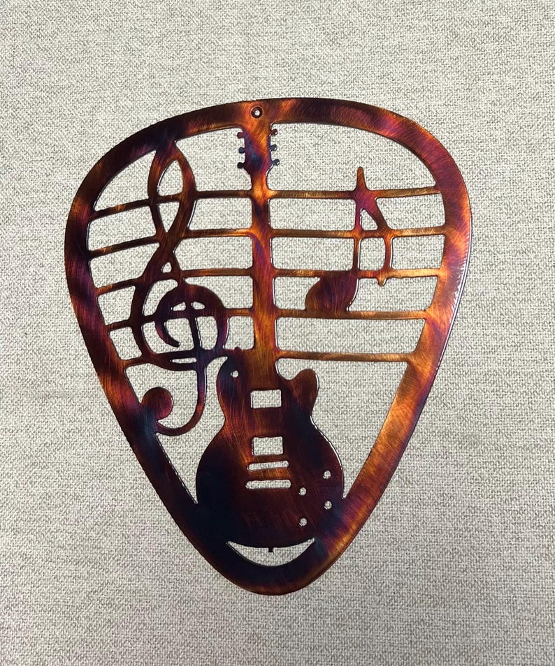 Guitar pick shaped metal wall art with Gibson SG inspired guitar, treble clef, and music notes in a hand-finished patina.