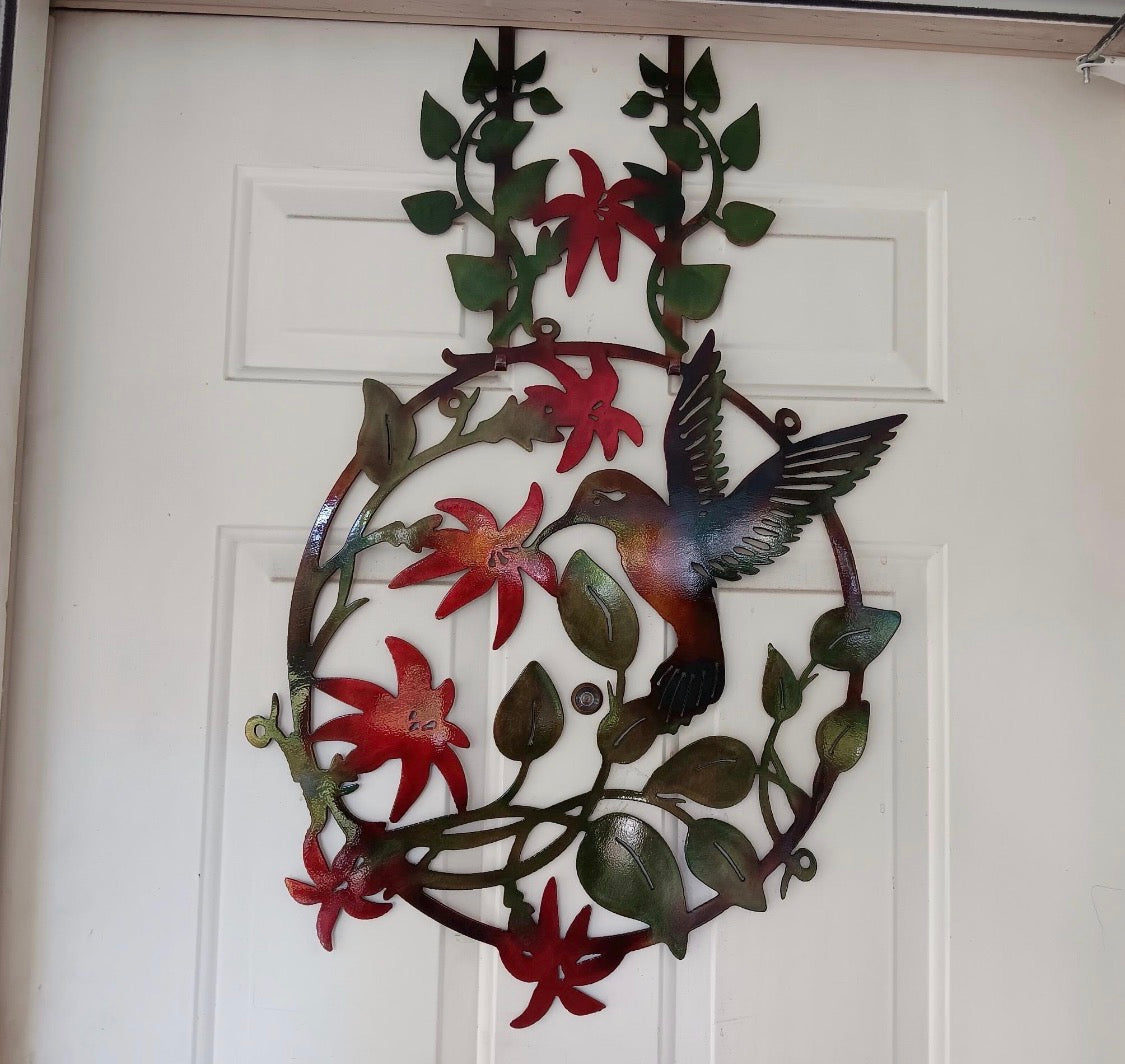 Full view of hummingbird and flowers metal door hanger displayed on a white exterior door.