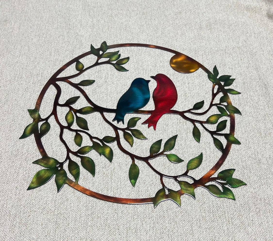 Handcrafted steel love birds wall art with colorful birds, green leaves, branches, and warm sun.