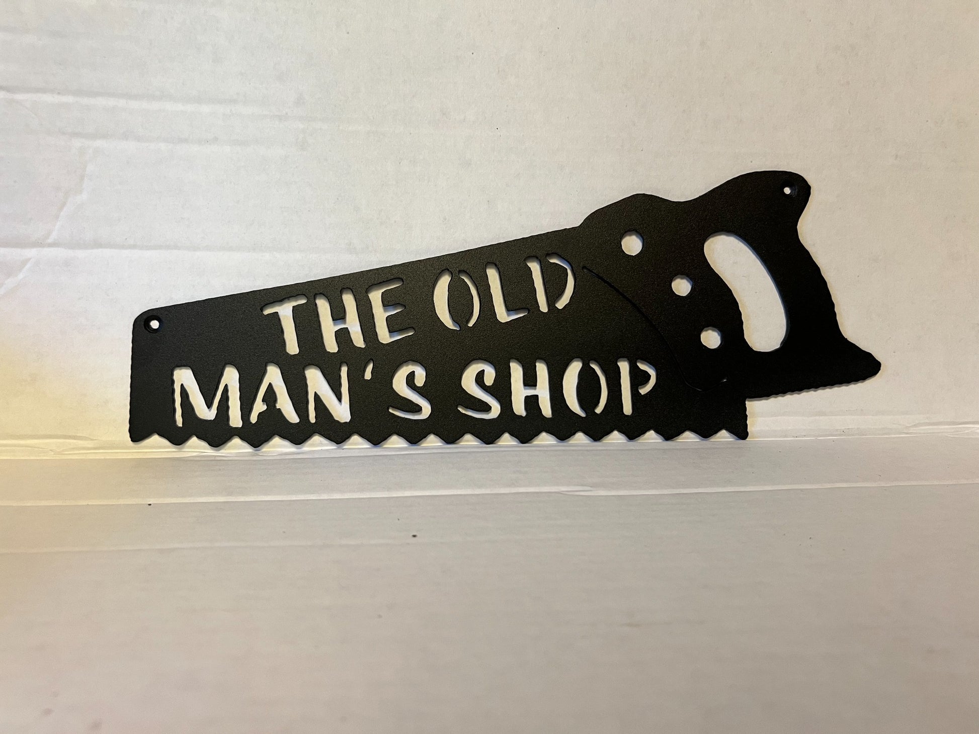 The Old Man's Shop handsaw-shaped metal wall sign in textured black finish