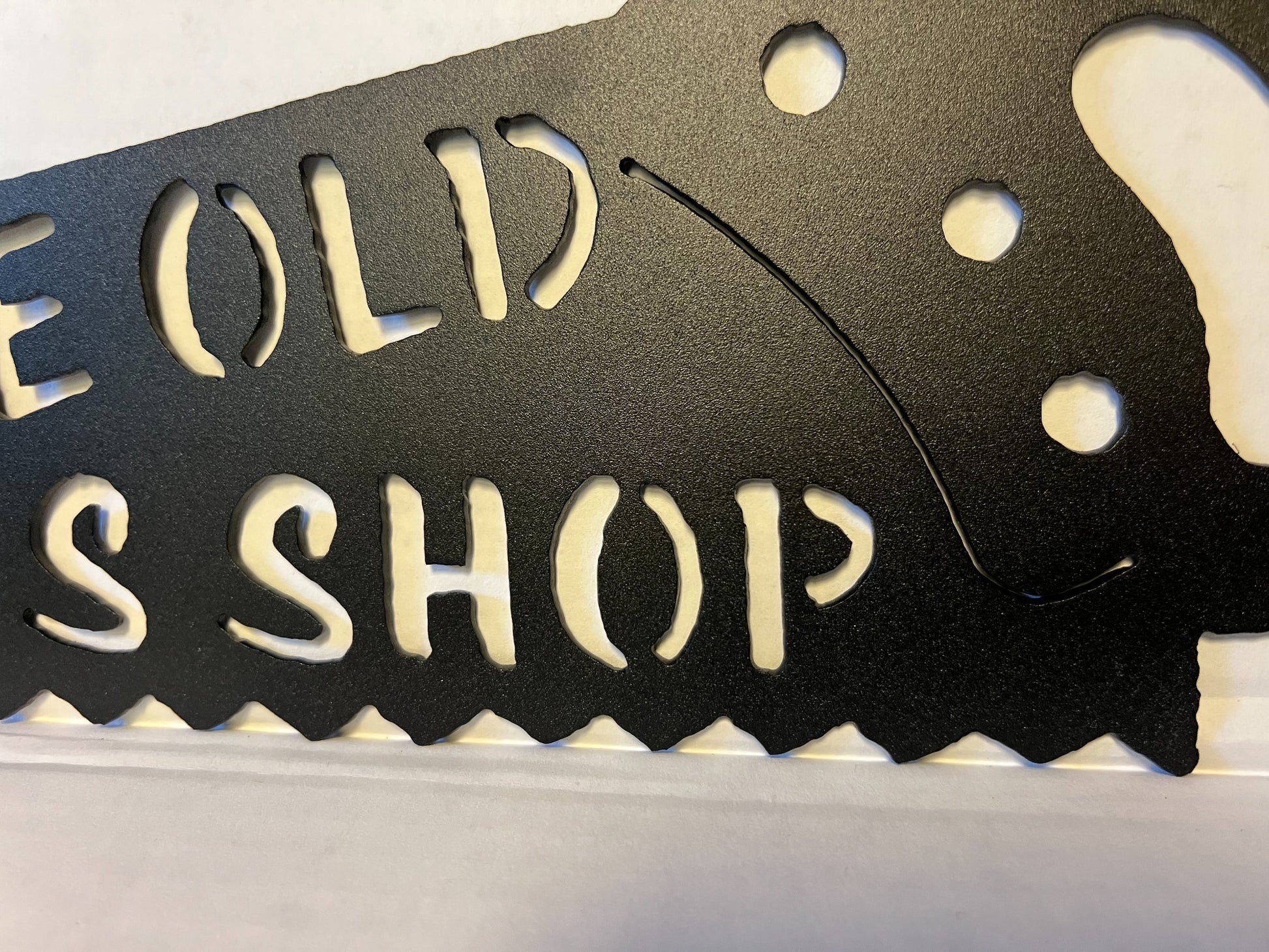 Close-up of the textured black finish and handle on the metal handsaw sign