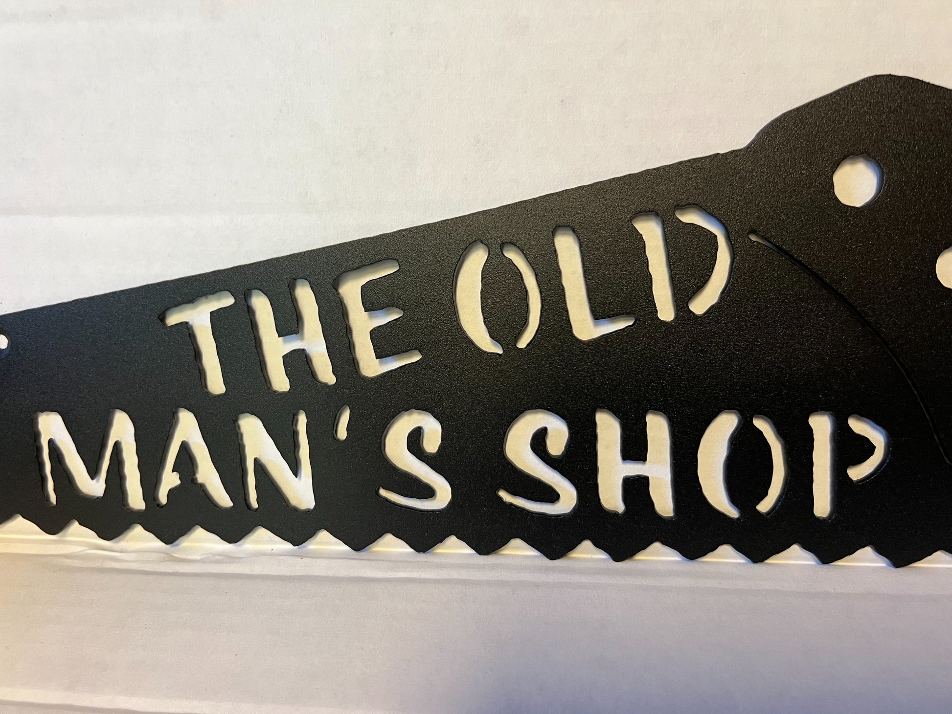 Close-up of plasma-cut Old Man's Shop lettering and saw teeth