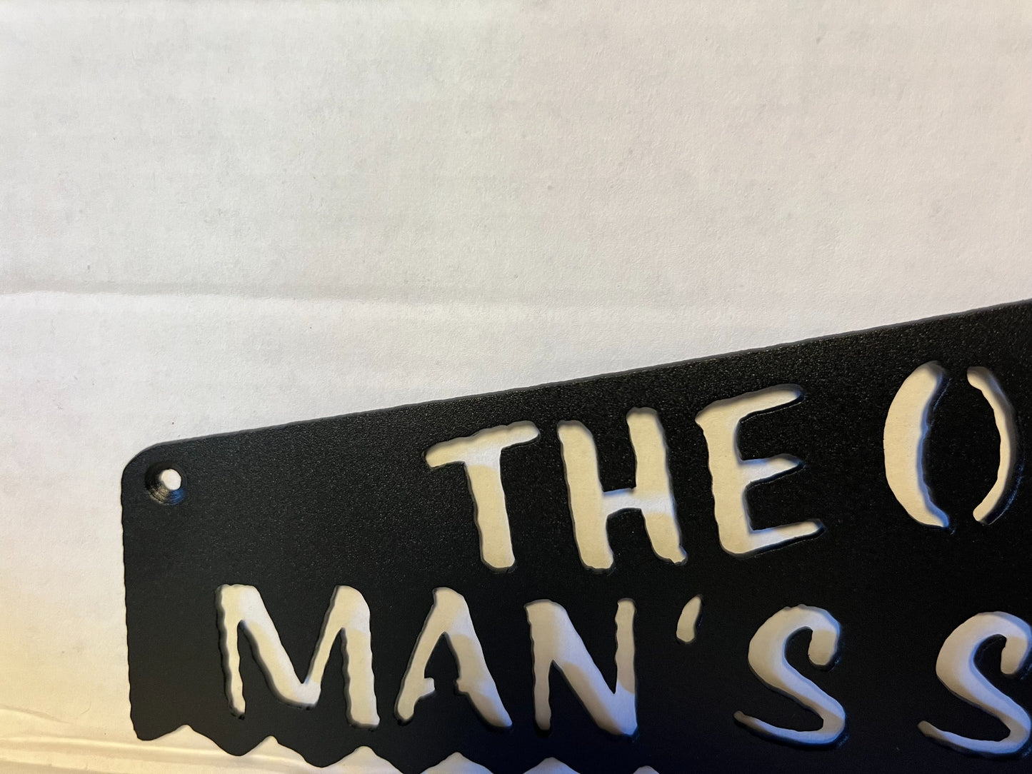 Close-up of mounting hole and plasma-cut lettering on the shop sign