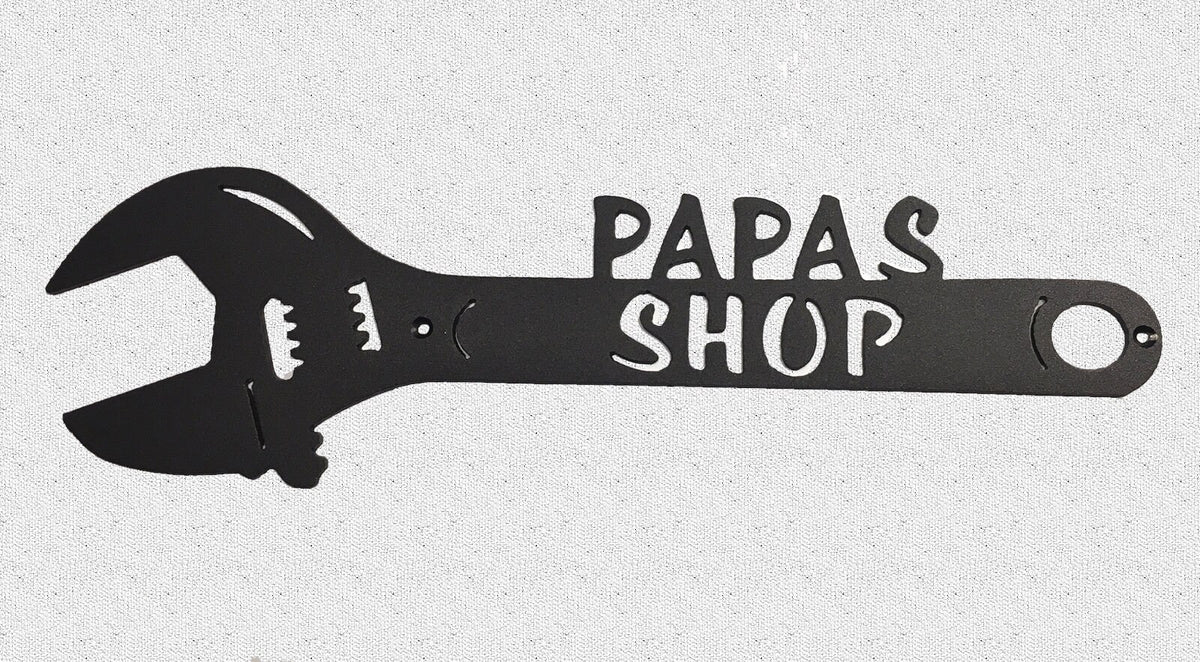 A crescent wrench metal art piece with the text 'PAPAS SHOP' cut out in the center, on a white background.