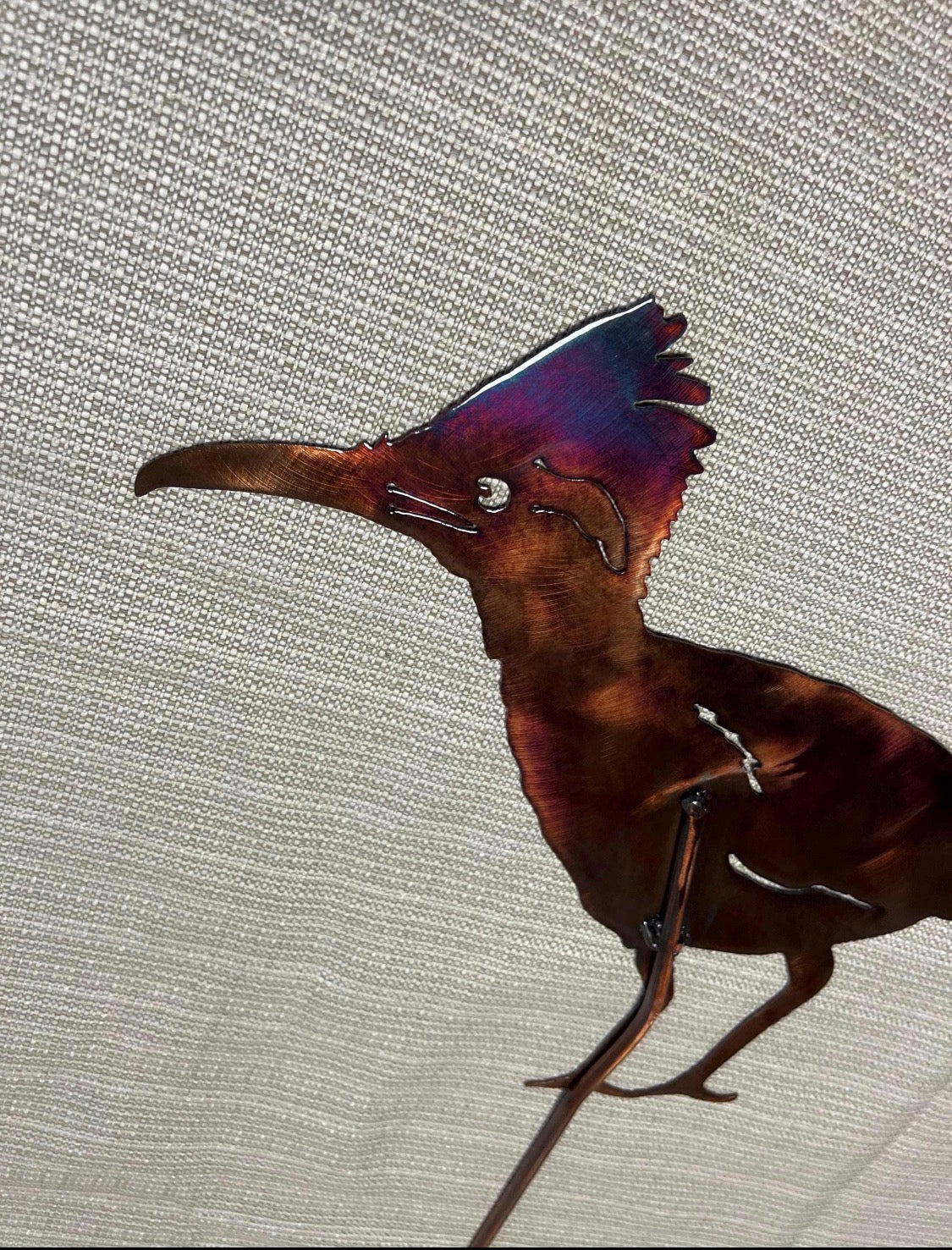 Close-up of the roadrunner crest and face showing copper, burgundy, blue, and purple patina colors.
