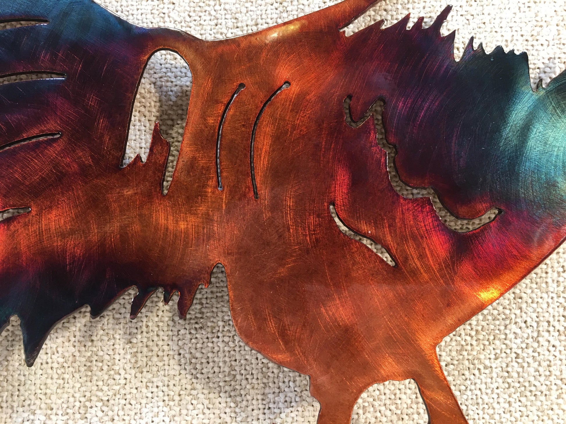 A wall-mounted metal art depiction of a rooster with a copper and patina finish, featuring airbrushed alcohol dye highlights.